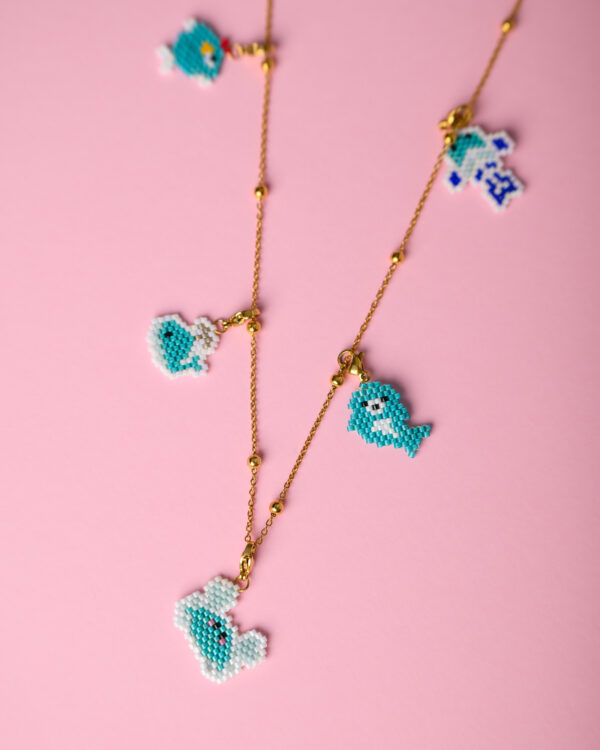 Miyuki sea animal charms necklace on a pink background by The Gem Stories.