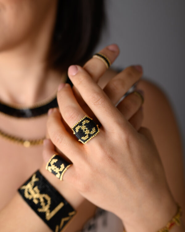 Close-up of model wearing Miyuki handmade black and gold beaded bracelet and rings from The Gem Stories.