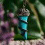 Close-up of a blue howlite tooth pendant with metallic accents on a silver chain