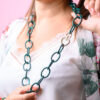 Woman holding a green chain necklace with a heart locket