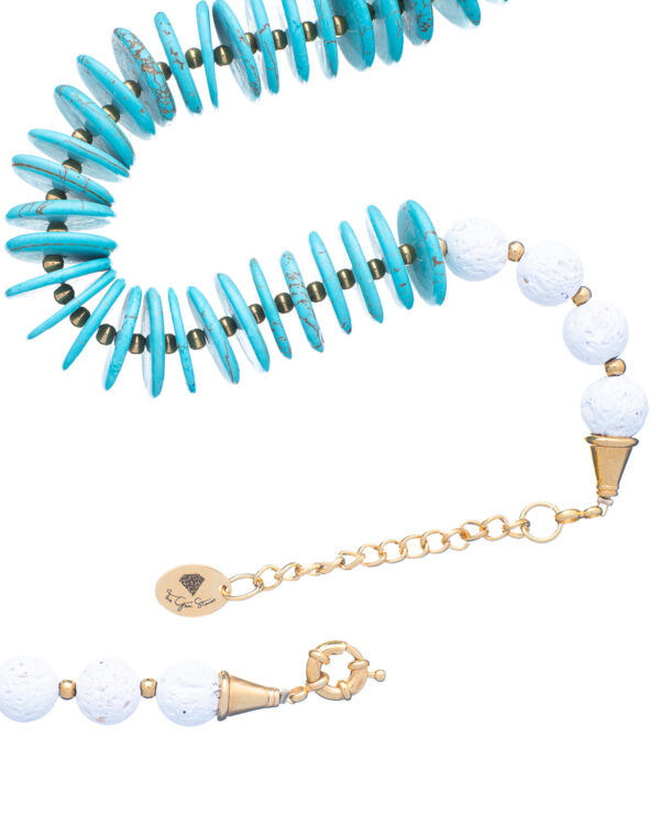 Close-up of a turquoise rondelle and white lava bead necklace with gold accents and clasp