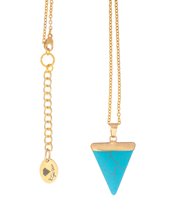 Close-up of a gold necklace with a blue howlite triangle pendant and an adjustable extender chain