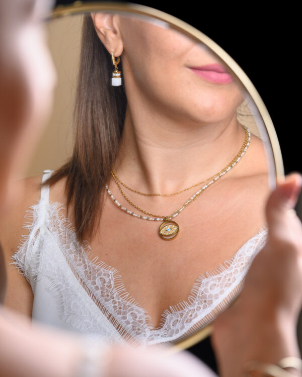Woman wearing an eye necklace with a petit pearl and matching earrings