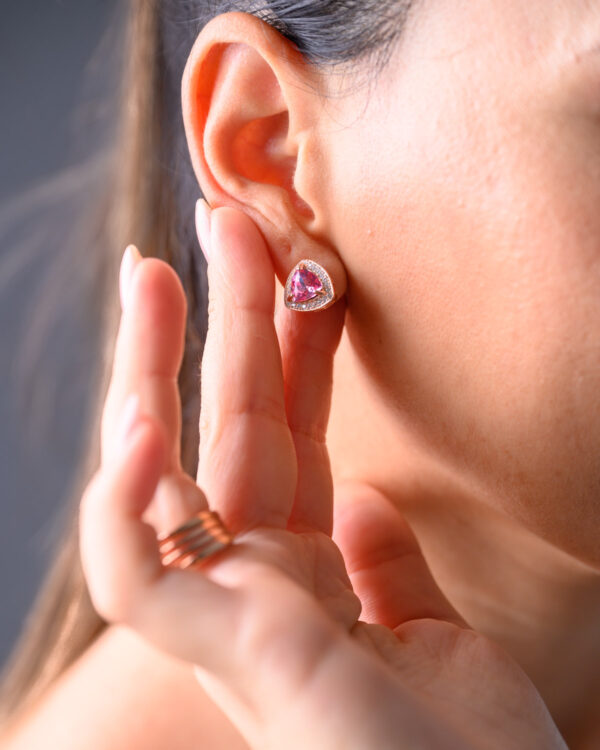 Close-up of a woman's ear adorned with a Brilliant Rose Silver Earring featuring a pink gemstone.
