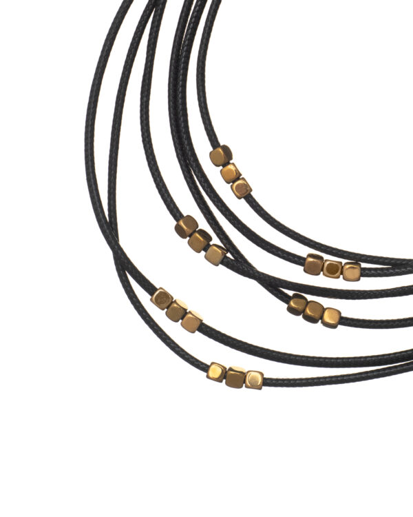 Close-up of a layered black leather necklace with gold beads