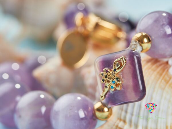 Close-up of an amethyst necklace featuring purple beads and a square amethyst charm with intricate gold detailing, displayed with seashells in the background