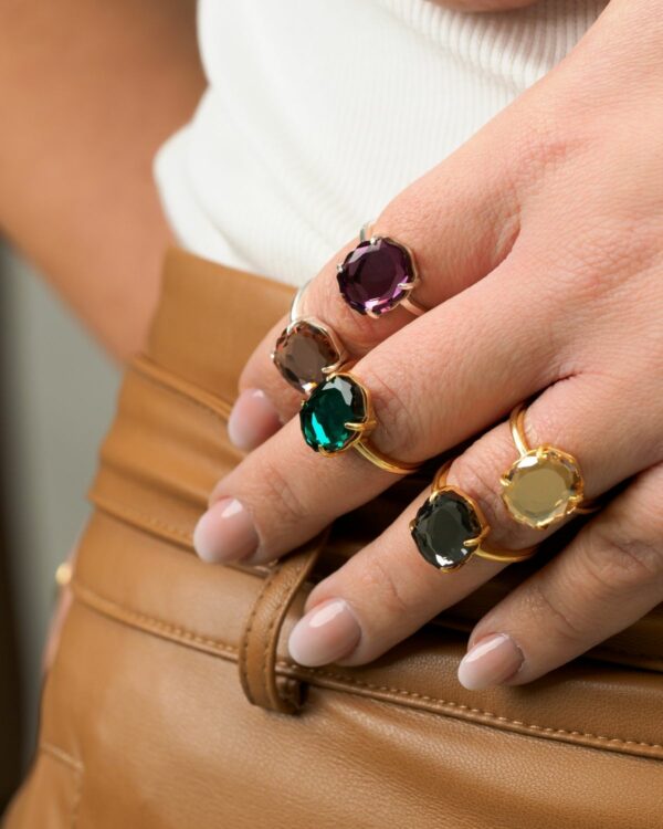 Close-up of hands wearing Baroque-style crystal rings in various colors.