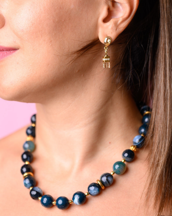 Woman wearing a blue jade necklace with gold accents and matching earrings