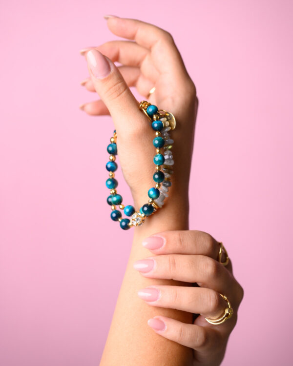 Close-up of a woman's hand holding Blue Tiger Eye Bracelets with vibrant blue stones