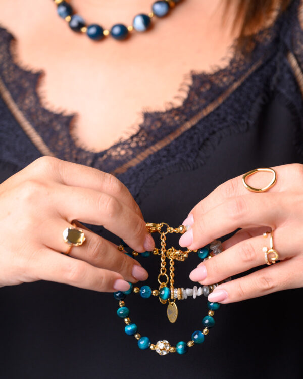 A woman's hands holding Blue Tiger Eye Bracelets with vivid blue gemstones