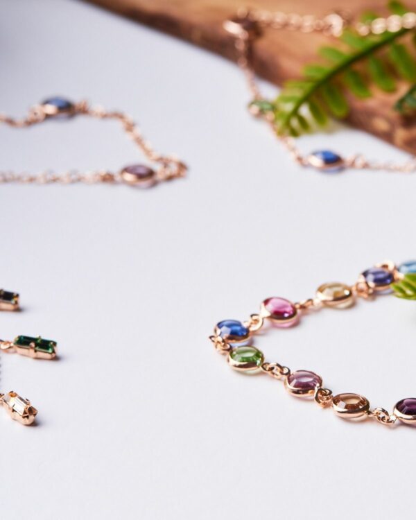 Close-up of Colorful 925 Sterling Silver Jewelry featuring multicolored gemstones in various hues like pink, green, and blue, elegantly set in a rose gold chain.