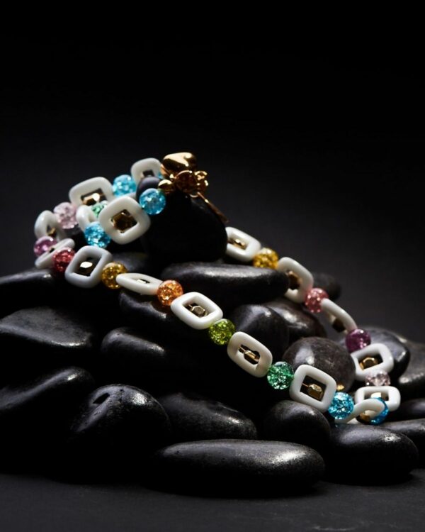 Colorful crackle crystals and square agate necklace on black stones background