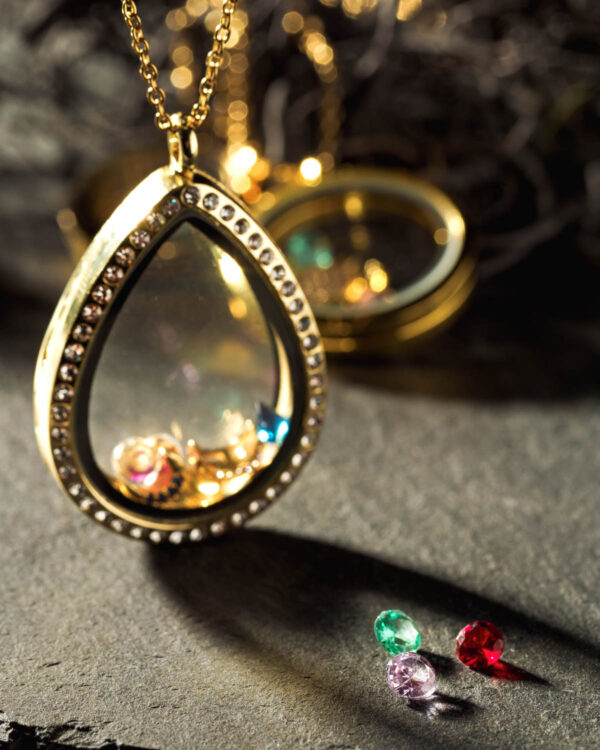 Close-up of a 35mm 24k gold plated teardrop floating memory locket containing colorful charms