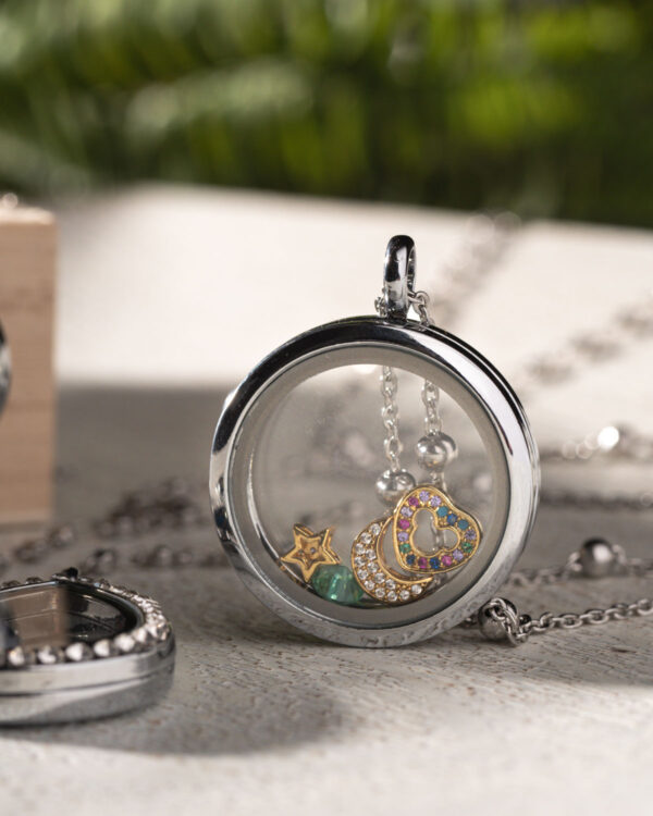 Close-up of a 30mm rhodium plated circular floating memory locket with colorful charms inside, displayed on a silver chain