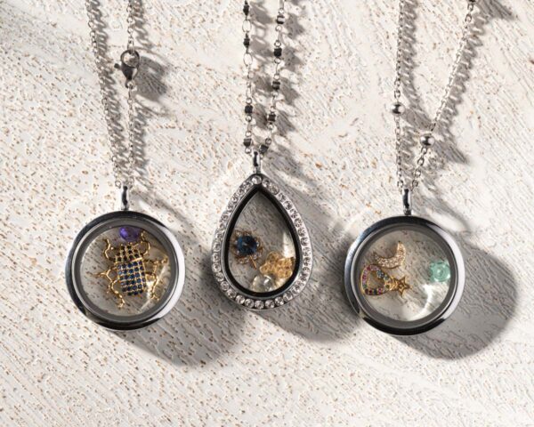 Three rhodium plated floating memory lockets in different shapes, each containing various gold charms