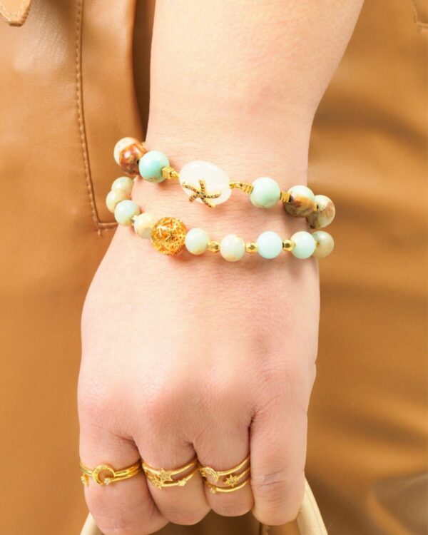 Summer-inspired gemstone bracelets and minimal gold rings on hand