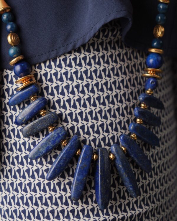 Lapis Lazuli Sticks Necklace Held by Person in Blue Outfit