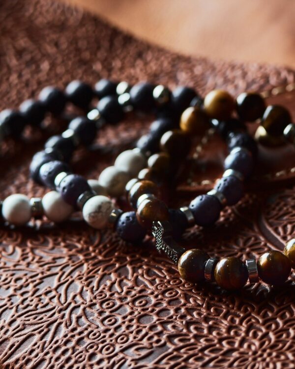Assorted leather men's bracelets with bead accents on an intricately patterned surface