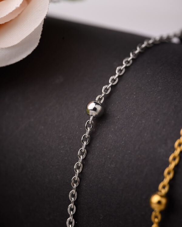 Close-up of a silver long chain necklace with a small bead detail