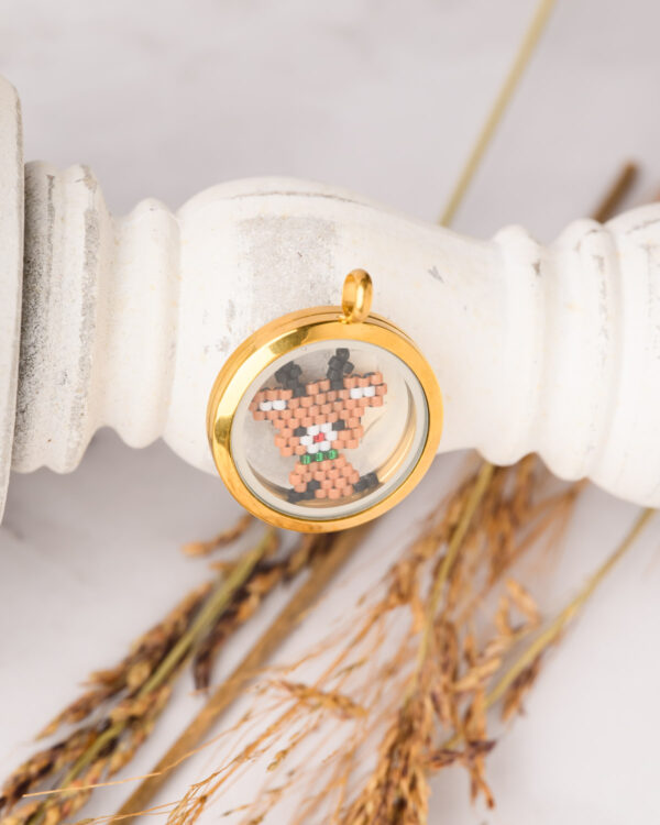 Memory locket featuring a Miyuki Cuties Element reindeer pendant with brown, black, white, and green beads inside a gold-framed glass locket.