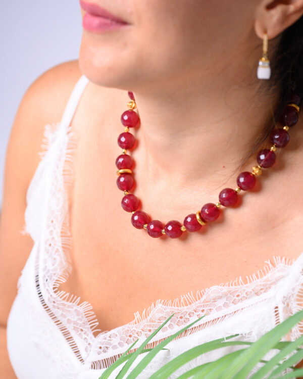 Woman wearing a red jade necklace with gold accents