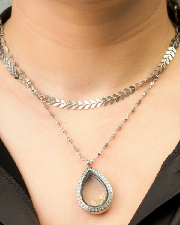 Close-up of a woman wearing a layered silver necklace set with a leaf design choker and a teardrop pendant necklace