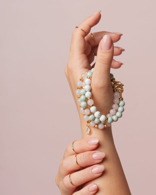 Close-up of a hand wearing a Rose Quartz Bracelet with Element, featuring delicate rose quartz beads and gold accents.
