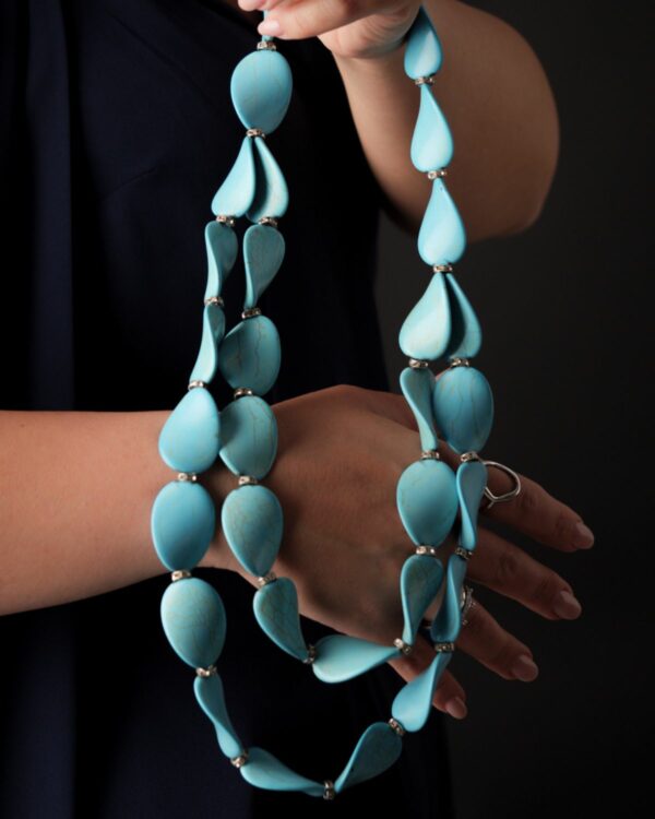 Woman holding a turquoise large chips necklace with a stylish design