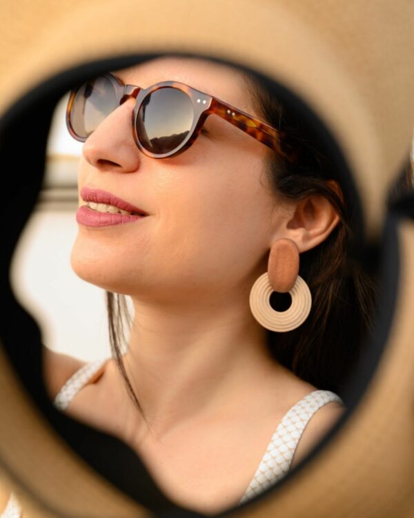 Close-up of a woman wearing stylish wooden earrings with a circular design