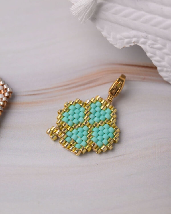 Close-up of a Miyuki Cuties Element Trefoil pendant with green beads and gold accents.