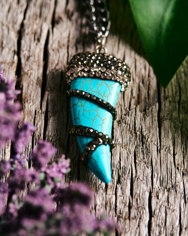 Close-up of a blue howlite tooth pendant with metallic accents on a silver chain