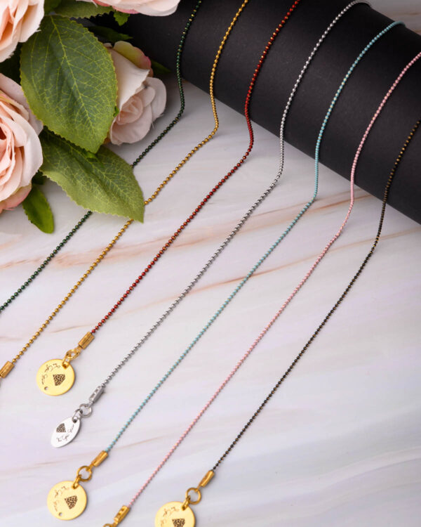 Close-up of long chain necklaces with colorful dotted designs and charm pendants