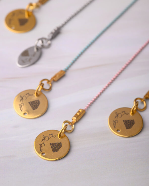 Close-up of long chain necklaces with colorful dotted designs and gold charm pendants