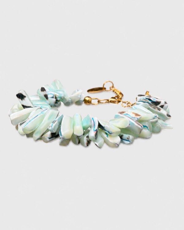 A chunky summer statement bracelet featuring polished, elongated shell shards in shimmering mother-of-pearl, mint green, and marbled blue tones, finished with a gold-plated lobster clasp and extender chain on a light grey background.