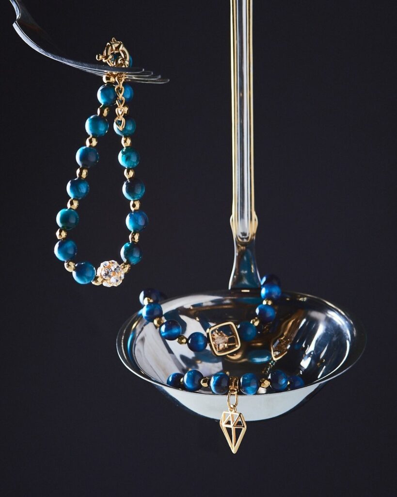 Elegant Tiger Eye Bracelets with rich blue beads and golden accents, displayed on a polished silver ladle.