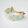 Handcrafted Miyuki loom bracelet featuring white, turquoise, and gold beads in a geometric design with an adjustable gold-toned clasp.