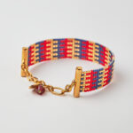 Intricate loom-stitched bracelet with Miyuki beads in red, blue, and gold striped design.