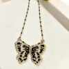 Black and gold Miyuki butterfly necklace displayed on a light surface.