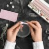 Hands cleaning jewelry with a brush, surrounded by sparkling earrings and rings in a jewelry tray, alongside cleaning tools.