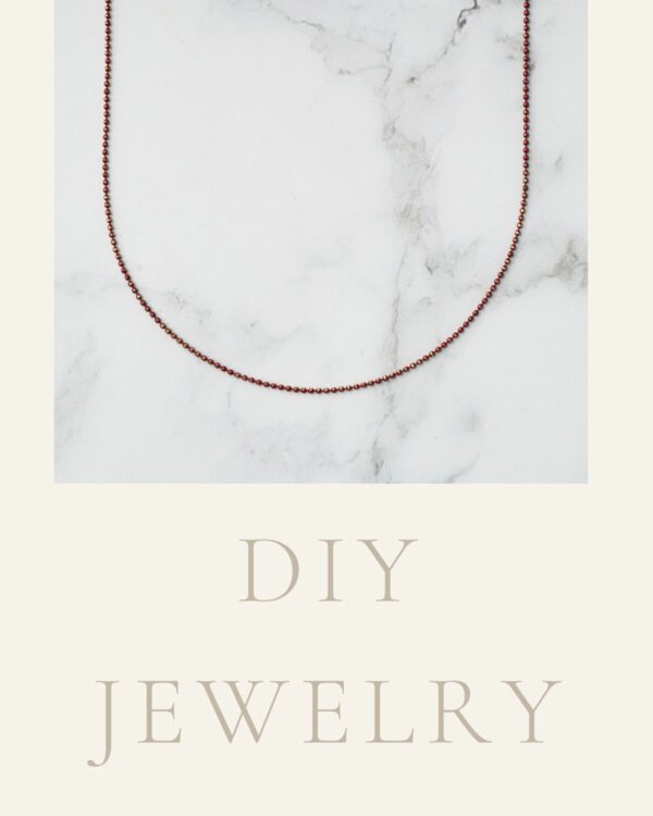 Long chain necklace adorned with red and gold dots, showcasing a stylish and vibrant design.