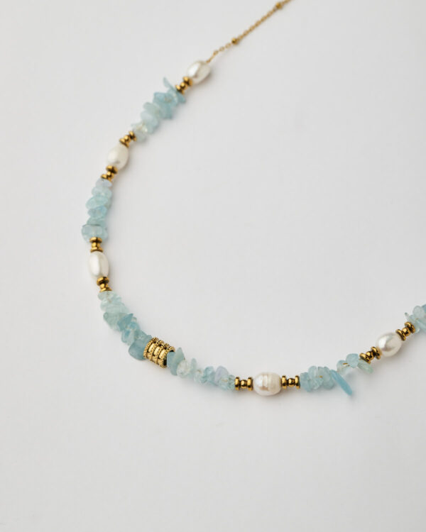 Close-up of aquamarine and pearl necklace with gold-plated details
