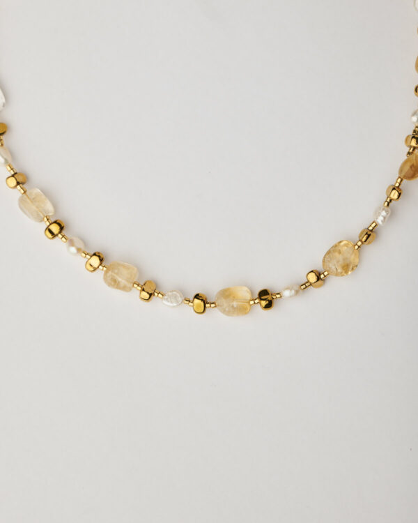Close-up of handmade citrine and pearl necklace with gold plated details