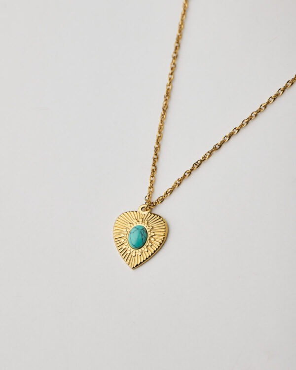 Close-up of gold heart pendant with turquoise stone