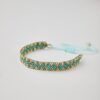 Close-up of Miyuki friendship bracelet with turquoise and gold chevron pattern