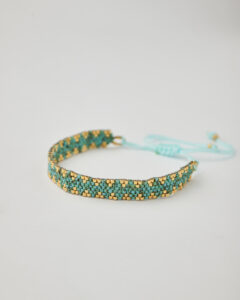 Close-up of Miyuki friendship bracelet with turquoise and gold chevron pattern