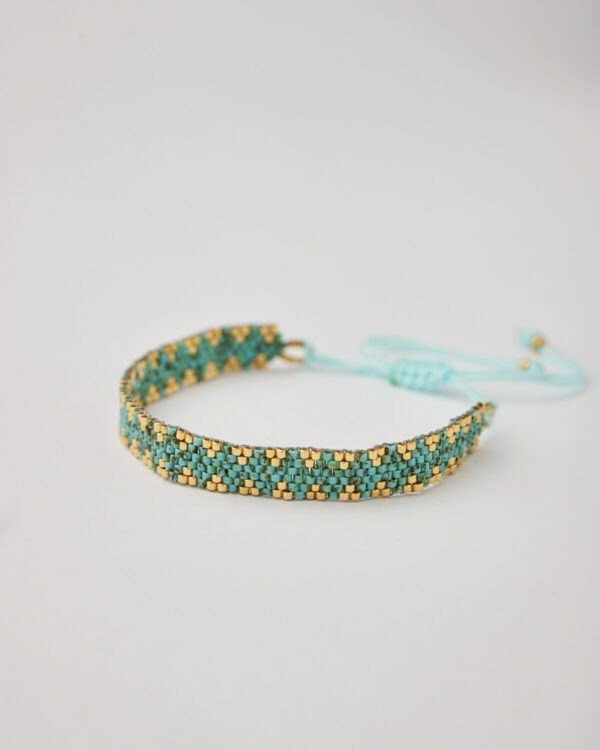 Close-up of Miyuki friendship bracelet with turquoise and gold chevron pattern