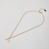 Gold necklace with whale tail pendant on white background