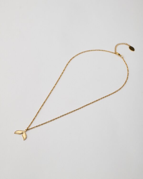 Gold necklace with whale tail pendant on white background