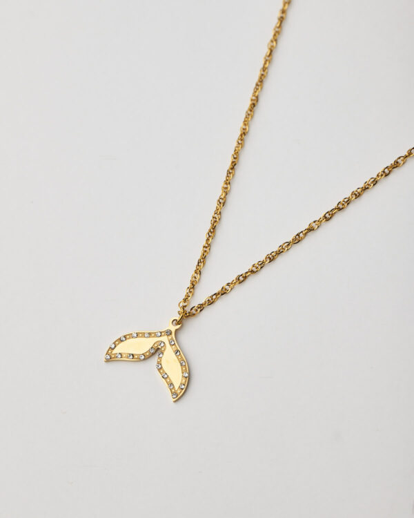Close-up of gold whale tail pendant with crystals