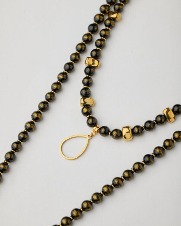 Close-up of black beaded necklace with 24k gold plated disc and gold spacers